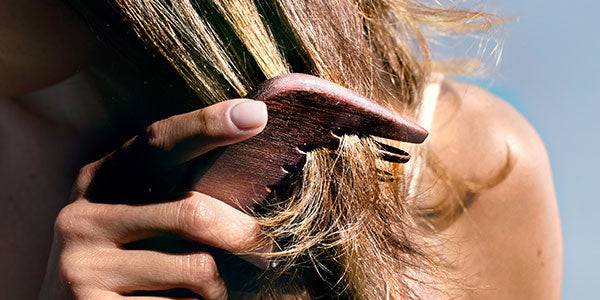 Peine de madera desenredando el cabello sin tirones; cuidado capilar L’Occitane para reducir quiebre y frizz.