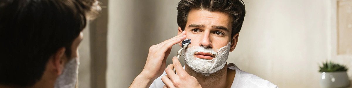 Hombre usando espuma de afeitar L’Occitane, cuidado facial que protege la piel sensible durante el rasurado.
